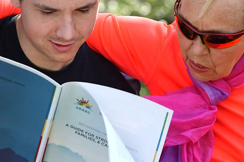 Stroke survivor and family catrgiver viewing SRABC guide book